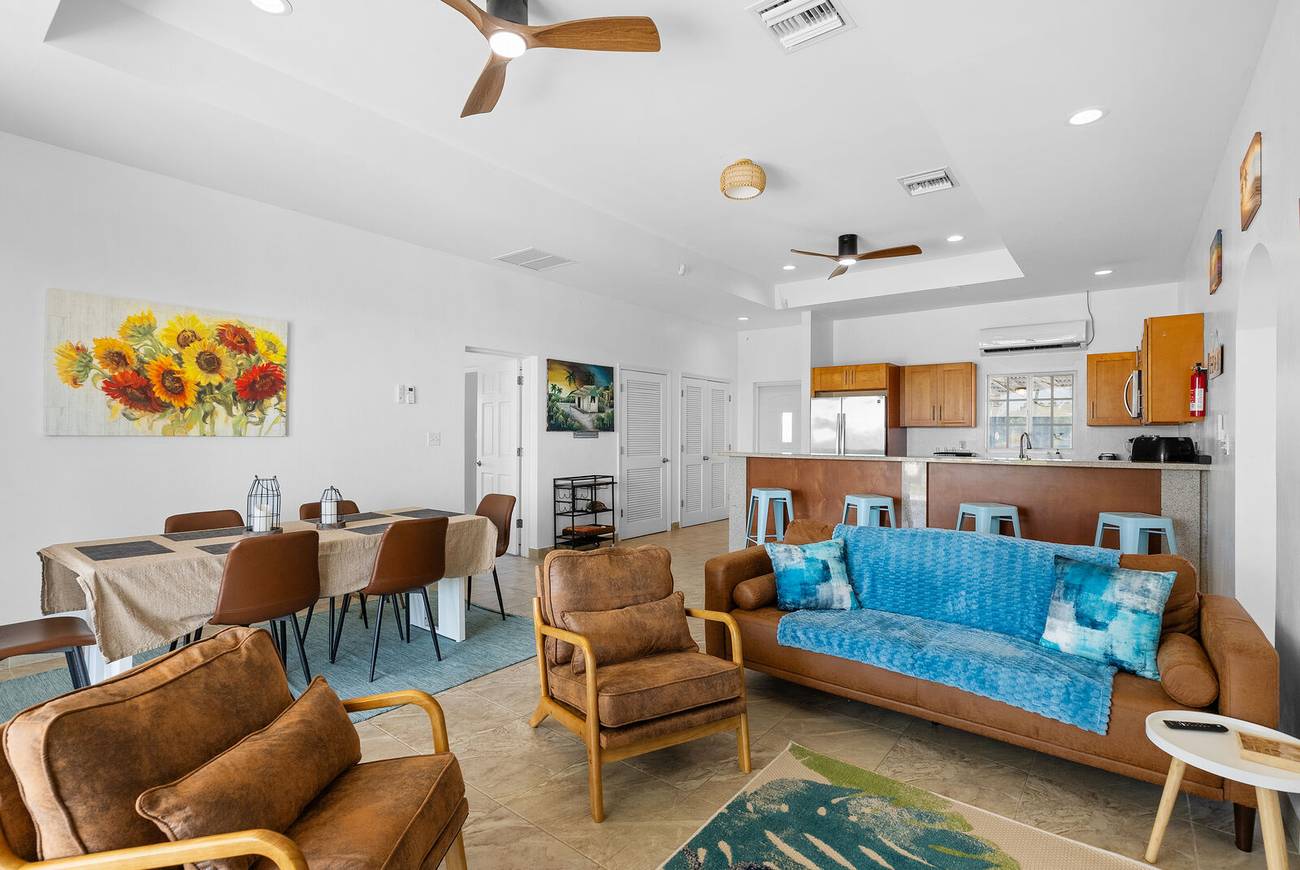 Open plan living room with blue sofa, leather armchairs and dining table