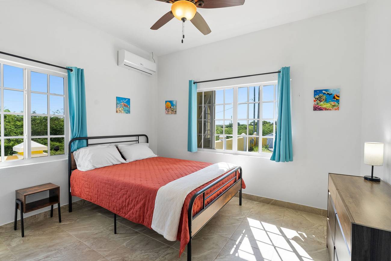 Second bedroom with coral bedspread and two windows