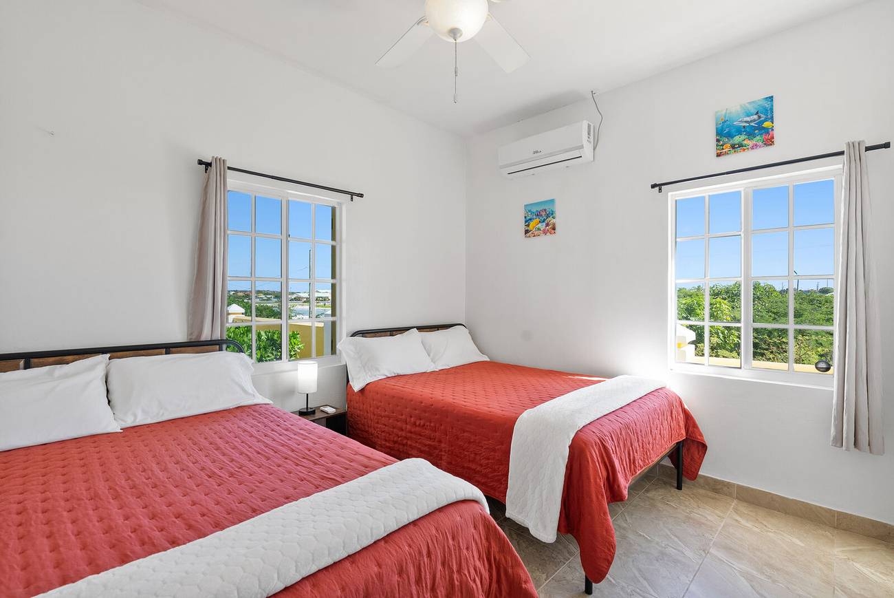 Third bedroom with two full beds and coral bedspreads