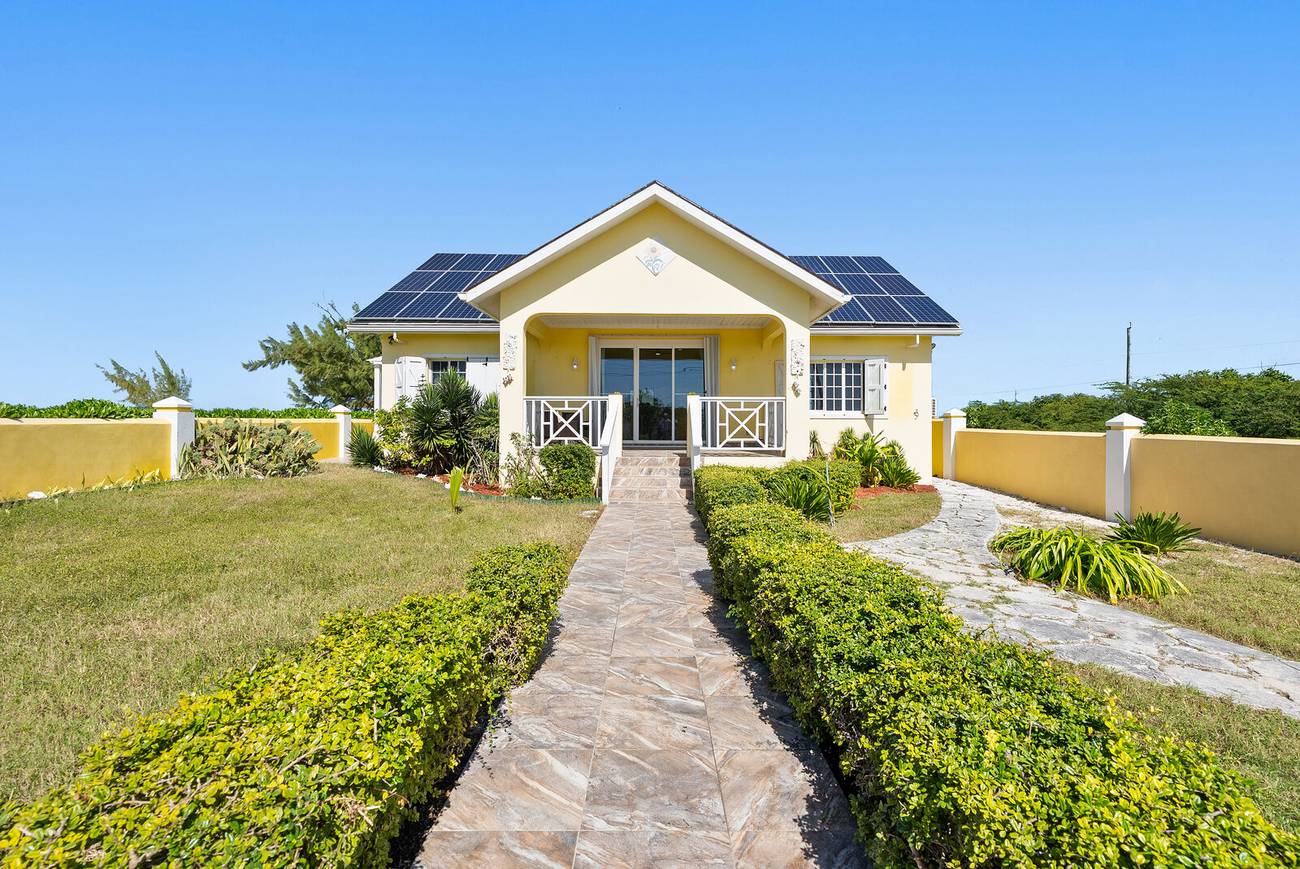 Front of the yellow villa with stone path through the garden