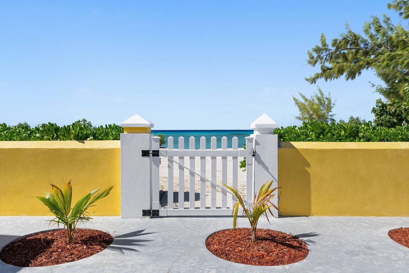 White garden gate opening directly onto the beach and sea